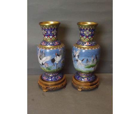 A good pair of Chinese cloisonn&eacute; enamel vases decorated with a frieze of cranes, wading and flying over lilies, on pie