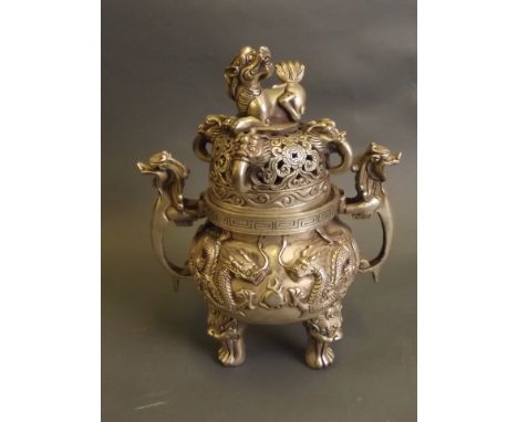 A Chinese silvered metal censer on tripod supports with relief decoration of dragons chasing the flaming pearl, with Fo dog k