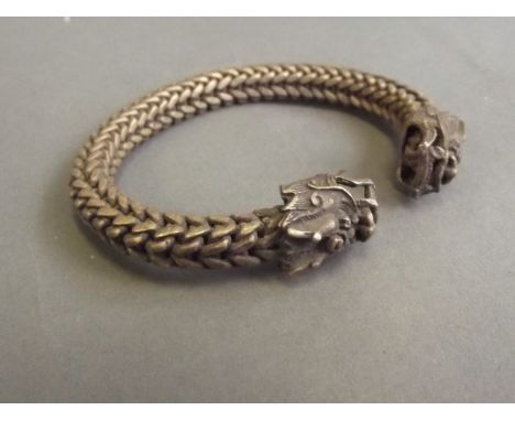 A Chinese silvered metal rope bangle with dragon head decoration, 3'' wide