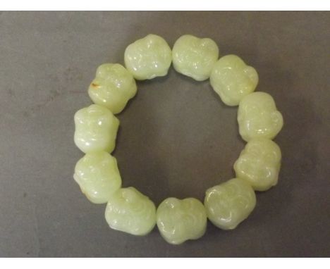 A jade bracelet linked by eleven carved Buddha heads, 3½'' diameter