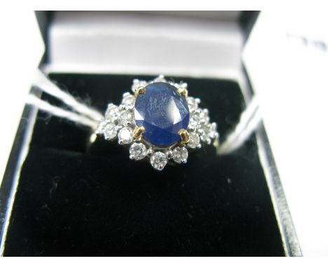 An 18ct Gold Sapphire and Diamond Cluster Dress Ring, oval four claw set to the centre, within border of uniform brilliant cu