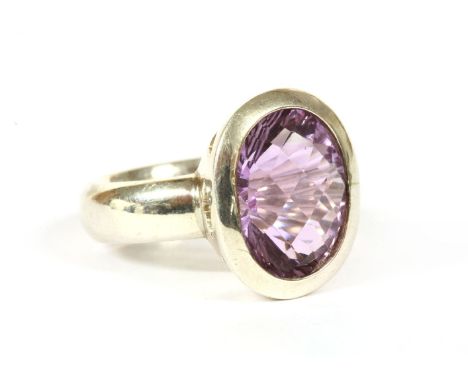 A sterling silver single stone amethyst ring, with an oval chequer cut amethyst, rub set to a plain collet with a court secti