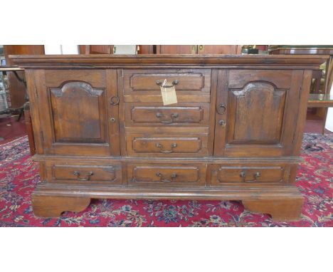 A 20th century teak sideboard, having three small drawers flanked by two cupboard doors above an arrangement of three small d