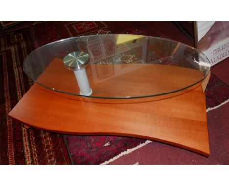 A contemporary low table, by B&amp;B Italia, with a swivel oval glass top raised above a wavy cherry wood veneered under tier