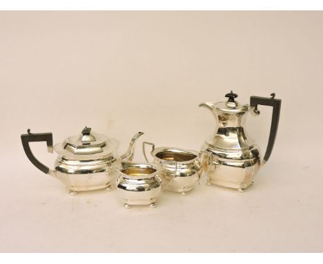 An early 20th century silver three piece tea set, the pot with faceted body ebonised handle and standing on short ball feet, 