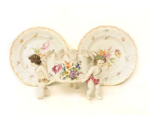 A late 19th century German porcelain bowl, supported by three cherubs, with painted flower sprays, underglaze blue 'AR' mark.