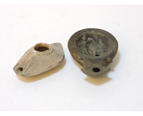 A pottery oil lamp, 9cm long and another Roman terracotta oil lamp, the centre depicting gladiators 10.5cm