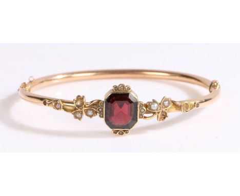 A 9ct yellow gold hinged bangle set with one octagonal cut garnet.Approx. measurements: 12.00 x 10.00 x 4.46mm.With seed pear