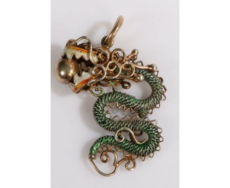 A yellow metal Chinese pendant with green and red enamel dragon holding a ball in its jaws. Length 33mm. Weighing 4.70 grams.