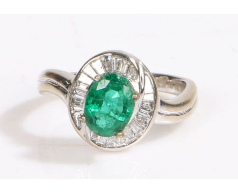 An 18ct white gold oval cut emerald and diamond cluster ring.Approx. emerald carat weight: 1.15cts.Approx. total diamond cara