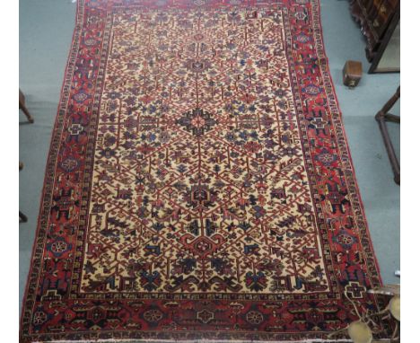 A cream ground Heriz rug with geometric designs in a red border, 333cm x 234cm Condition Report: Rug is in good general condi