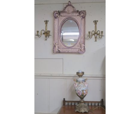 A pink Continental ceramic wall mirror with cherubs etc with replacement glass (def), a pair of brass wall sconces and a cera