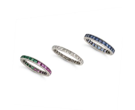 NO RESERVE - A SET OF THREE GEMSET ETERNITY RINGS one set all around with a row of rectangular step cut emeralds and rubies, 