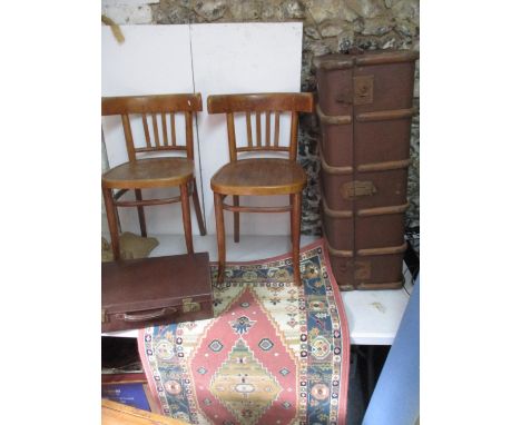 A canvas style trunk, a brown leather suit case, two rugs and two Bentwood style chairs 