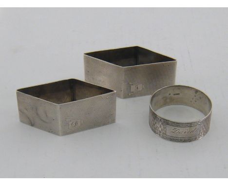 A pair of silver Art Deco rhomboid napkin rings with engine turned finish and reserves engraved D and J, by Walker & Hall, Sh