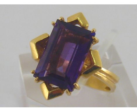 An amethyst dress ring, the large rectangular cut stone 11.5mm long, the yellow metal shank stamped '750', finger size N/O, 5