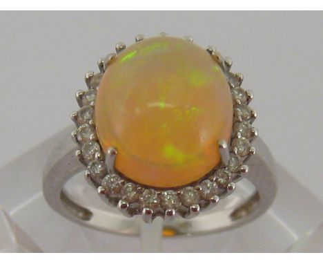 An 18 carat white gold, opal and diamond ring, the large domed cabochon opal 11.9 x 10.4 x 7 (deep) mm, in a surround of smal