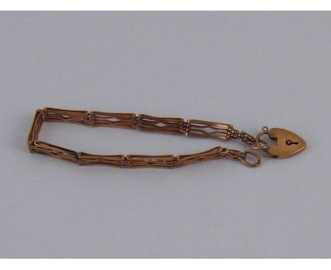 A yellow metal (tests 9 carat gold) gate bracelet with heart padlock clasp, approx 17cm long, 7.4 gms.
