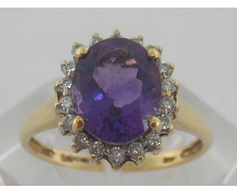 A 9 carat yellow gold, amethyst and diamond ring, the central oval stone 10mm long, in a surround of small brilliants, the sh