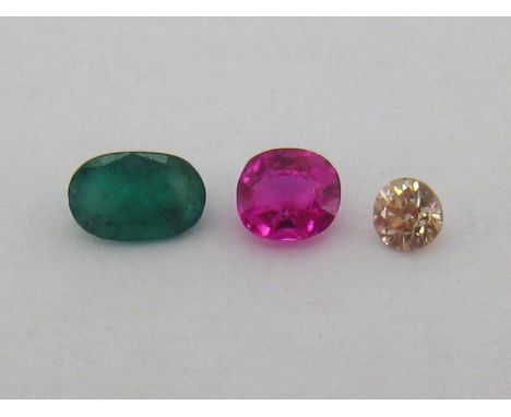 A mixed lot of three loose stones, including a small brilliant cut diamond, 3.2mm diameter, an oval cut emerald 6.2mm long, a