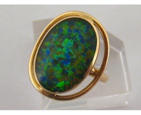 A 9 carat gold and opal doublet ring, the central oval stone 18.5mm long, the shank fully hallmarked, finger size O/P, 5gms C