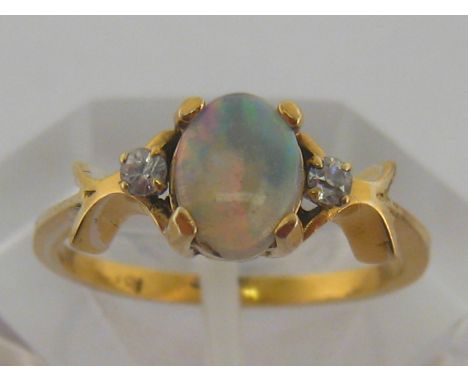 An opal ring, the central opal 7.2mm long, in a yellow metal mount, finger size L/M
Surface of the stone with some minor nics