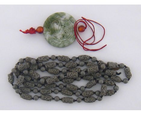 A Chinese circular jade pendant, cut with a dragon motif to the centre, 54mm diameter, on a red silk string, together with a 