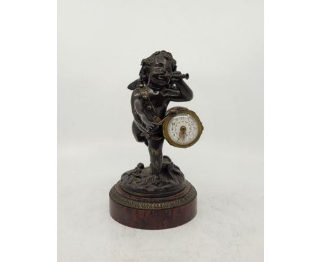 A 19th century French bronze and red marble figural mantel clock, fashioned as a putti blowing trumpet and banging on a drum,