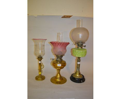 Victorian brass oil lamp with a cranberry glass shade together with two other brass oil lamps