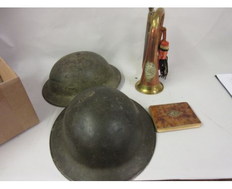 Two World War II helmets with leather liners and chin straps together with a Sutherland and Argyle bugle and a Royal Artiller