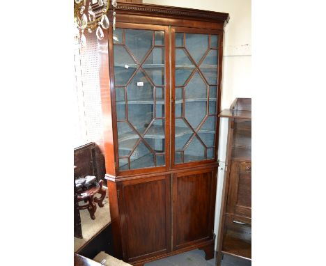 George III mahogany floor standing corner cabinet, the moulded cornice above two astragal glazed doors with two panelled door