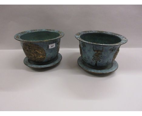 Pair of Chinese porcelain jardinières with drip trays, each relief moulded with symbols on a blue ground and signed with squa