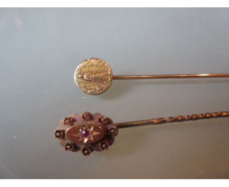 Two gold stick pins, one decorated with a lady