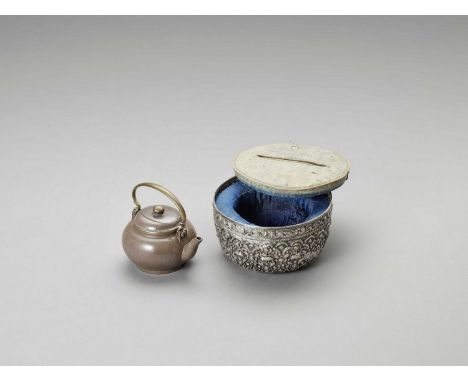   A YIXING TEAPOT INSIDE A LARGE SILVER BOWL, C.1900  The Yixing ceramic teapot: China, c. 1900. The silver bowl: Tibet, c. 1