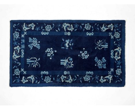   A ‘FLORAL’ CHINESE WOOLLEN RUG  China, 20th century. The woven carpet in blue hues with scattered flowers and butterflies. 