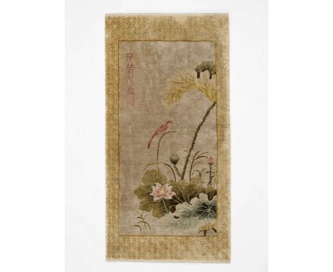   A CHINESE WOOLLEN ARTIST RUG  China, 20th century. The carpet with a bird perched on a flowering lotus branch, calligraphy,