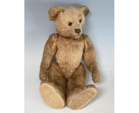 A vintage Teddy Bear, with black button eyes, straw filling, sewn nose, light orange plush and felt pads, 14in high.