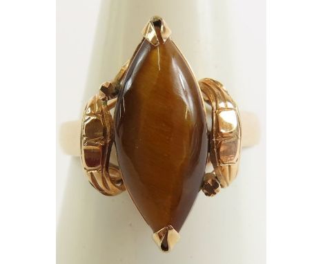 A tiger's eye stone set ring, the single cabochon marquise shaped stone approximately 16mm x 6.5mm, with decorative shoulders
