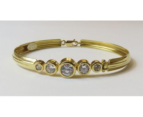 An oval bangle set with five graduated cubic zirconia's, marked '750', 6cm across, 10.71g gross