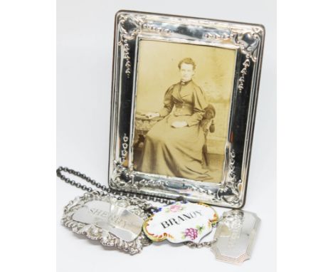 A mixed lot of hallmarked silver comprising two decanter labels and a photograph frame together with an enamel decanter label