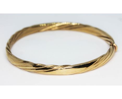 A gold bangle of twisted form, marked 9Kt and also with 9ct gold import marks, approx. diam. 6cm, wt. 11.25g.  