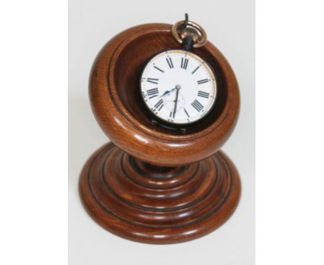 A gun metal over sized pocket watch on oak watch stand, the watch having Roman numerals and seconds subsidiary dial on white 