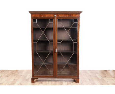 An early 20th Century mahogany bookcase, with moulded and dentil cornice above a pair of astragal glazed doors opening to rev