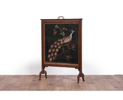 An early 20th Century mahogany framed fire screen, with silk on silk embroidered panel depicting a peacock perched on a tree 