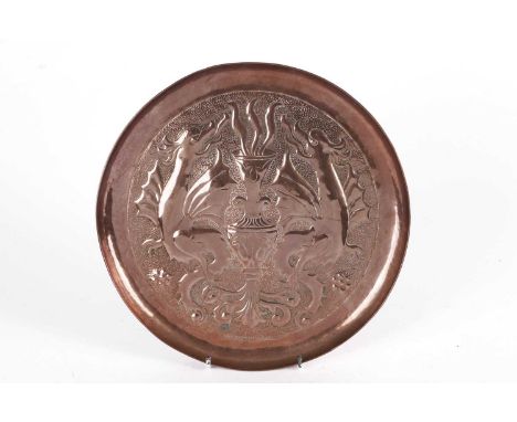 A Keswick School of Industrial Arts circular copper charger, decorated with dragons, stamped ‘W.H. Mawson KHI Keswick’, 29cms