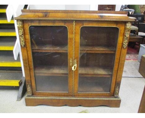 A late Victorian string inlaid walnut pier cabinet with gilt metal mounts and a curved frieze, over a pair of glazed doors on