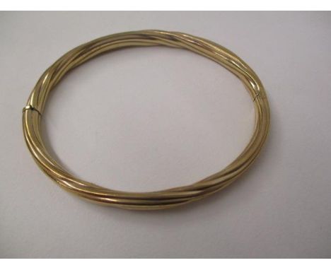 A gold coloured metal bangle with rope twist style ornament, stamped 9kt, 11.7g total 