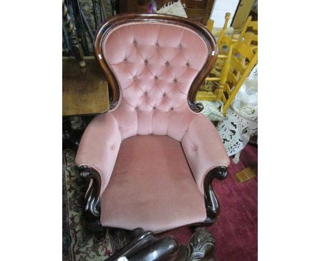A Victorian mahogany button back armchair, upholstered in pink dralon, scrolled show ends and turned front legs with ceramic 