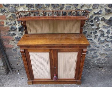 A Regency rosewood chiffoniere with a spindled, gallery shelf over a pleated fabric, panelled back, above a pair of pleated f