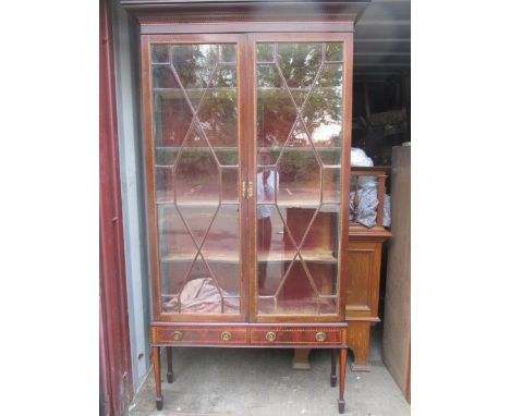 An Edwardian inlaid mahogany display cabinet with carved, moulded cornice, over a pair of astrigal glazed, panelled doors and